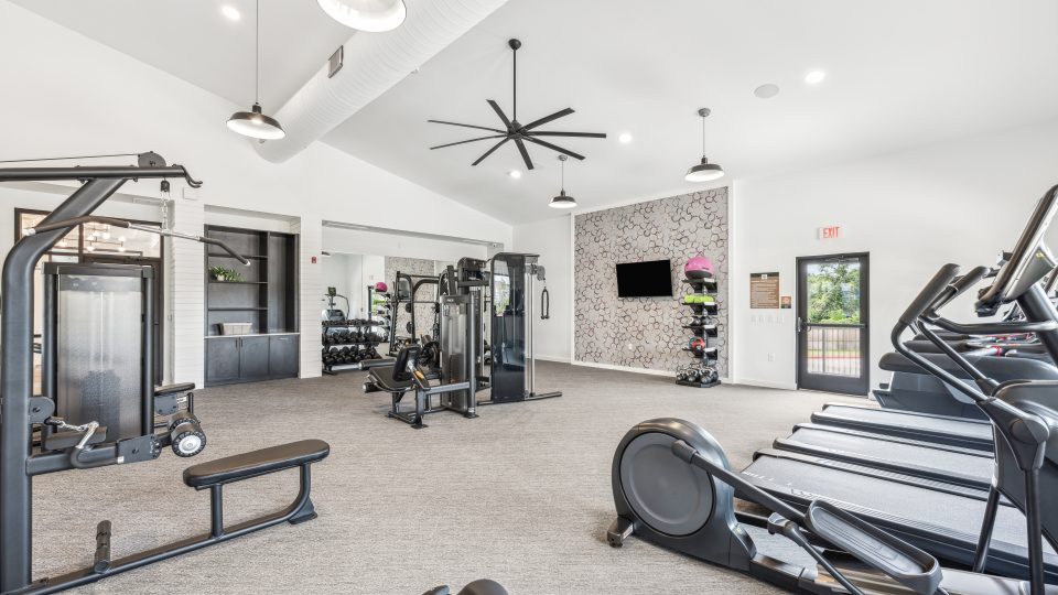 a gym room with tread machines and a ceiling fan at The Rushcreek